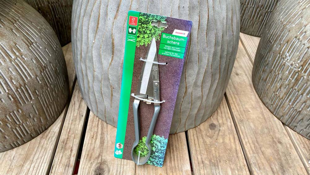 Buchsbaumscheren getestet: Ein verpacktes Produkt lehnt an einem Blumentopf.