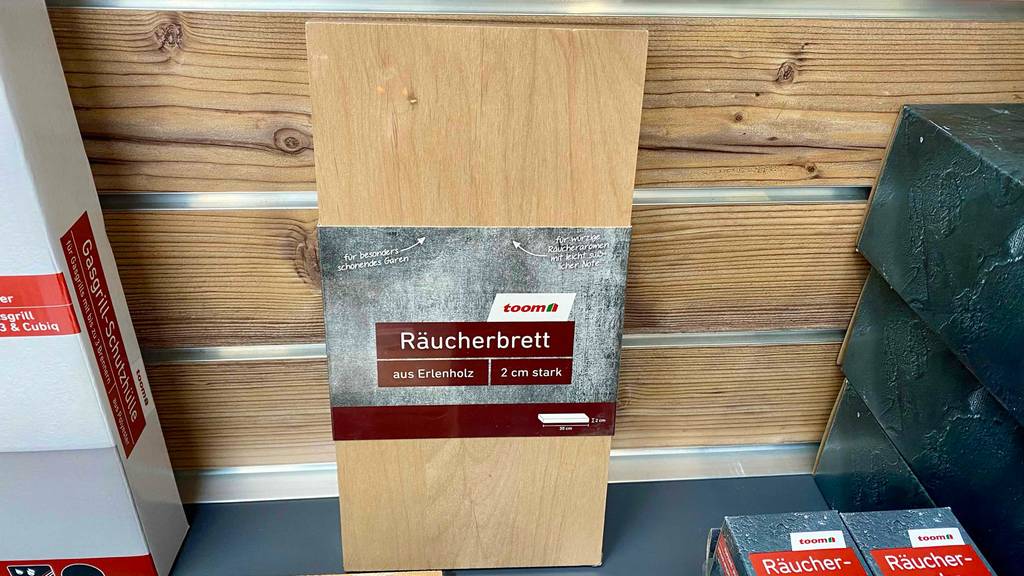 Ein getestetes Räucherbrett lehnt an einer Holzverkleidung neben anderen Produkten.