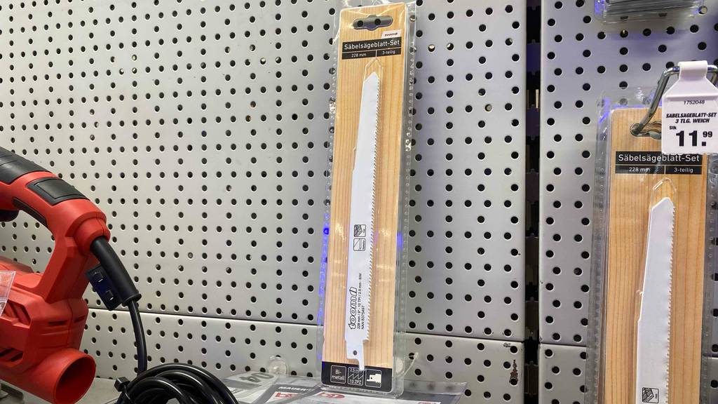 Säbelsägeblätter getestet: Eine transparente Packung Säbelsägeblätter lehnt an einem Lochblech neben anderen Produkten.
