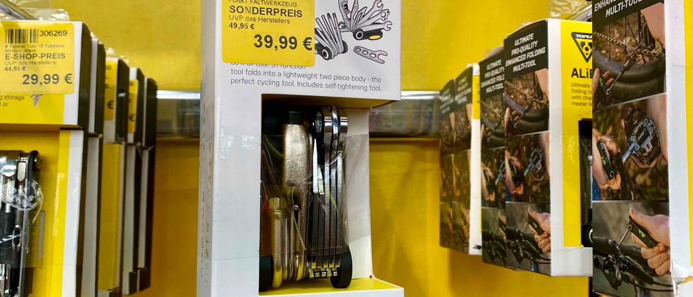 Im Test: Ein Fahrrad-Multitool mit Preisangabe auf der Verpackung hängt neben anderen Produkten in einem Regal.