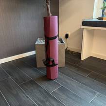 Die Toplus-Yogamatte steht eingerollt auf einem Fliesenboden