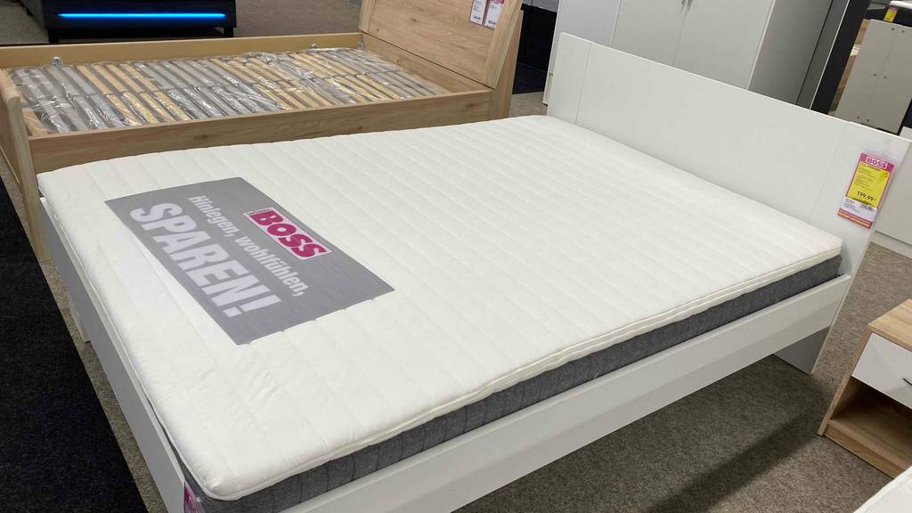 Bettgestell befindet sich neben einem getesteten Matratzentopper mit den Maßen 140x200 cm.