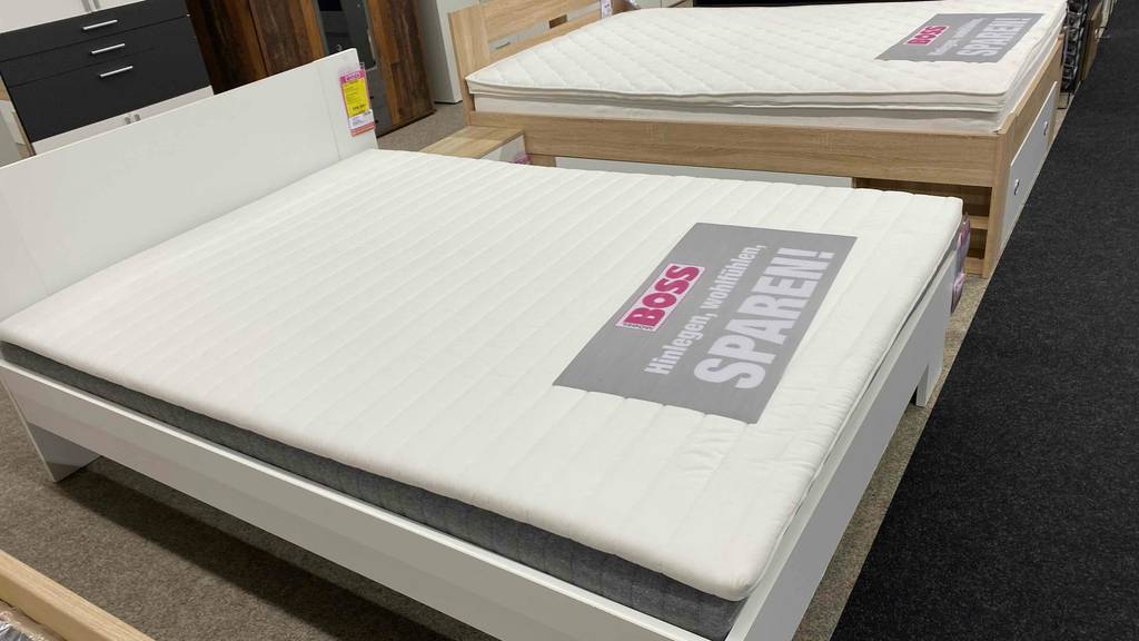 Ein Bett befindet sich neben einem getesteten Matratzentopper mit den Maßen 140x200 cm.