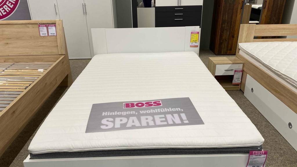 Ein getesteter Matratzentopper mit den Maßen 140x200 cm befindet sich neben anderen Betten im Möbelhaus.