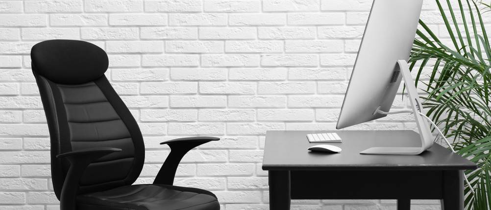 Topstar-Bürostuhl-Test: Ein schwarzer Bürostuhl mit Netzrücken vor einem modernen Schreibtisch.