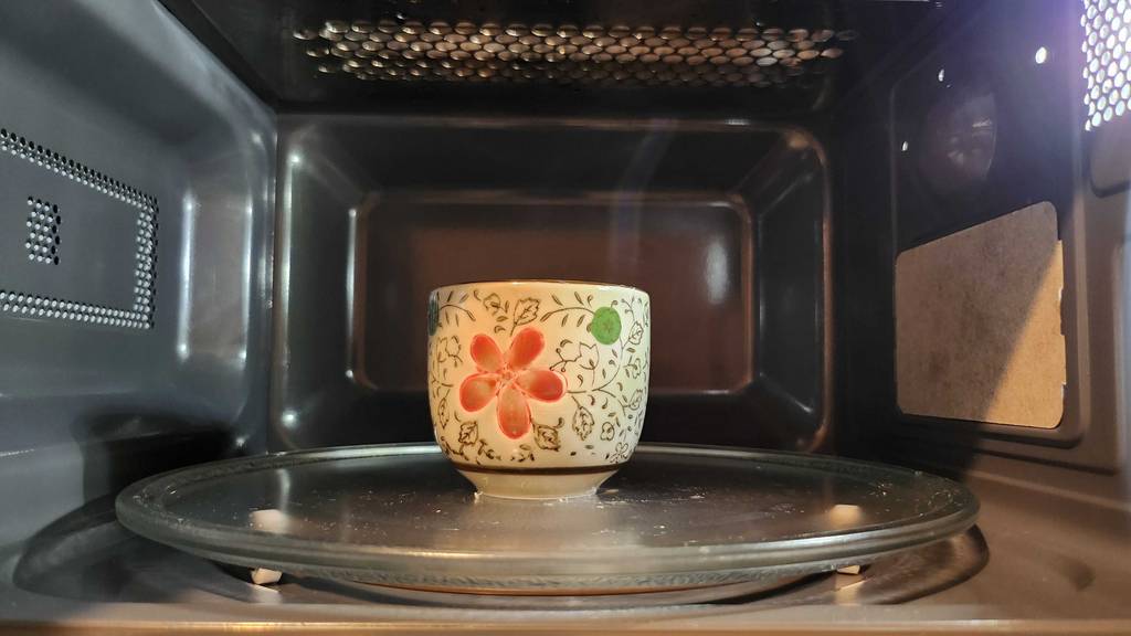 Eine Tasse mit Blumenmuster steht auf dem Glasdrehteller eine getesteten Toshiba-Mikrowelle.