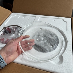 Eine Hand entnimmt aus dem Karton der Toshiba MW2-AG23PF(BK) einen Drehteller