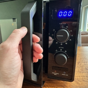 Eine Hand greift den Griff der Toshiba MW2-AG23PF(BK)