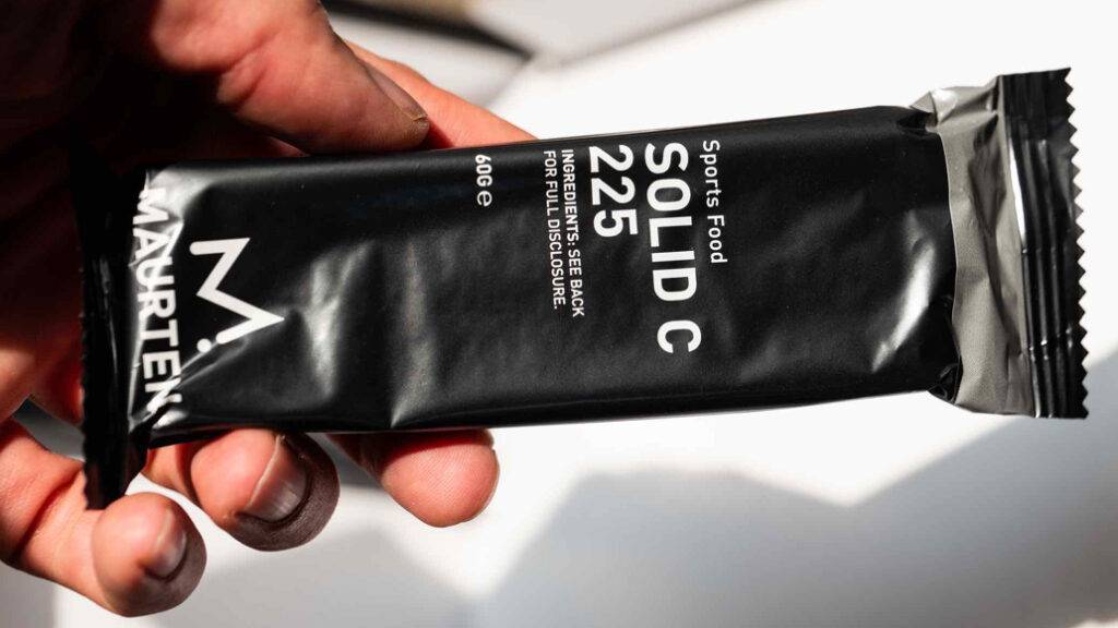 Im Test: ein Energieriegel der Marke Maurten in einer eleganten schwarzen Verpackung wird von einer Hand gehalten.