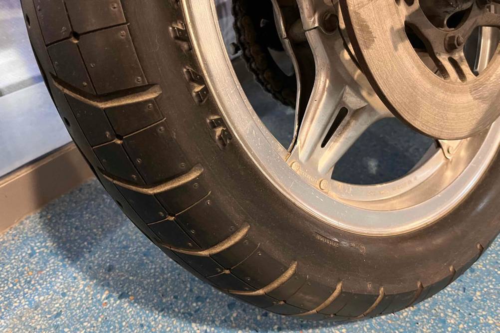 Nahaufnahme eines getesteten Motorradreifens inklusive Scheibenbremse.