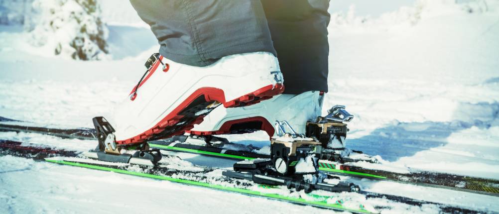 Tourenskischuhe im Test: weiße Skischuhe auf Skiern im Schnee.
