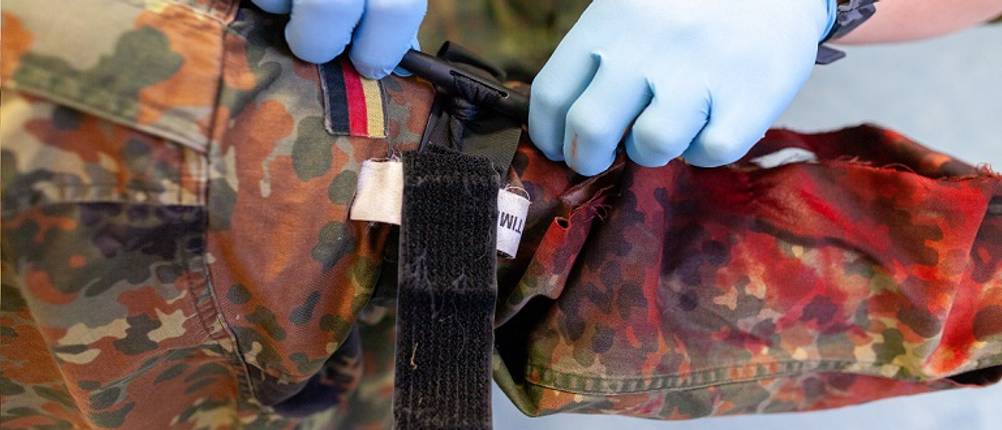 Tourniquet im Test: Mann, der Arm eines Soldaten mithilfe eines Tourniquets abbindet