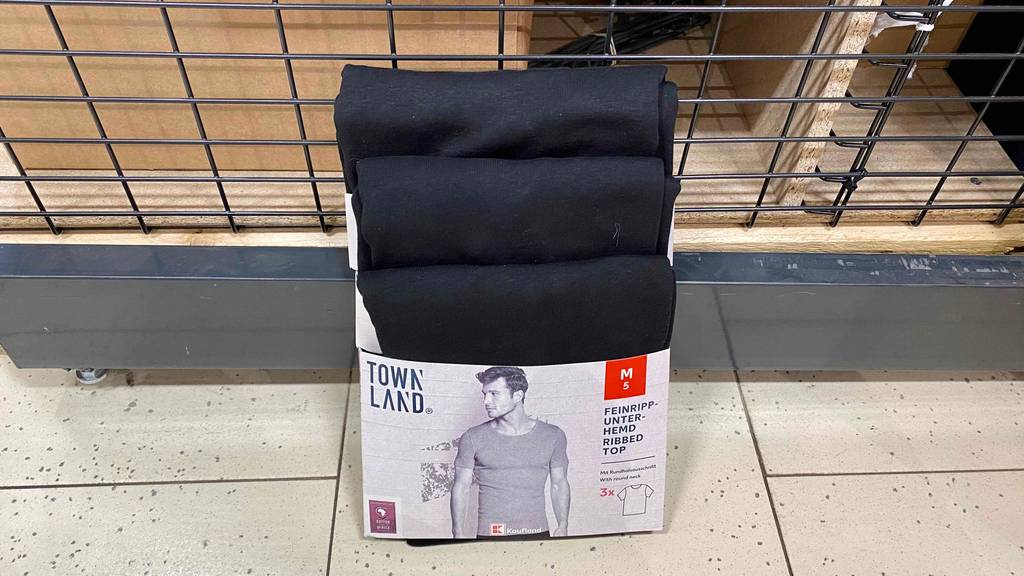 Dreierpack schwarze Unterhemden für Herren von Town Land lehnt zum testen an einem Gitterregal.