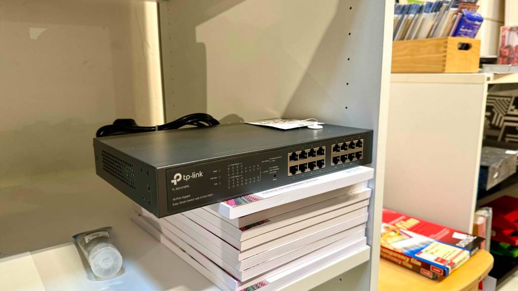 Getestet: Ein 16-Port-Gigabit-Switch steht in einem weißen Regal auf mehreren Büchern.