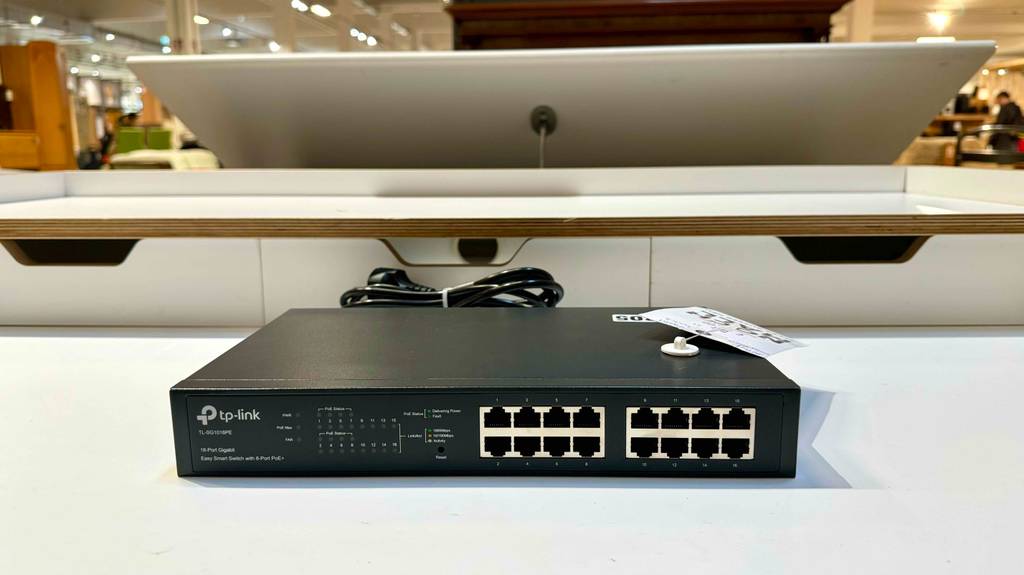 Ein getesteter 16-Port-Gigabit-Switch steht auf einem weißen Regal im Verkaufsbereich.