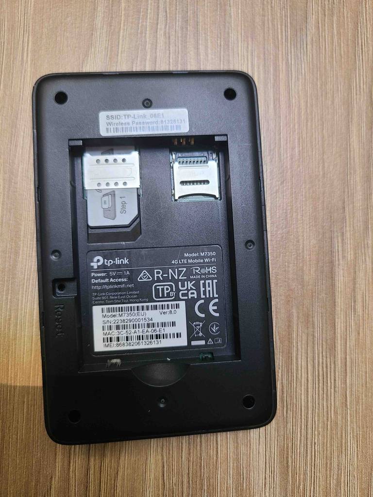 Gesamtansicht vom geöffneten Batteriefach des getesteten mobilen WLAN-Routers, der auf einer Holzoberfläche liegt.