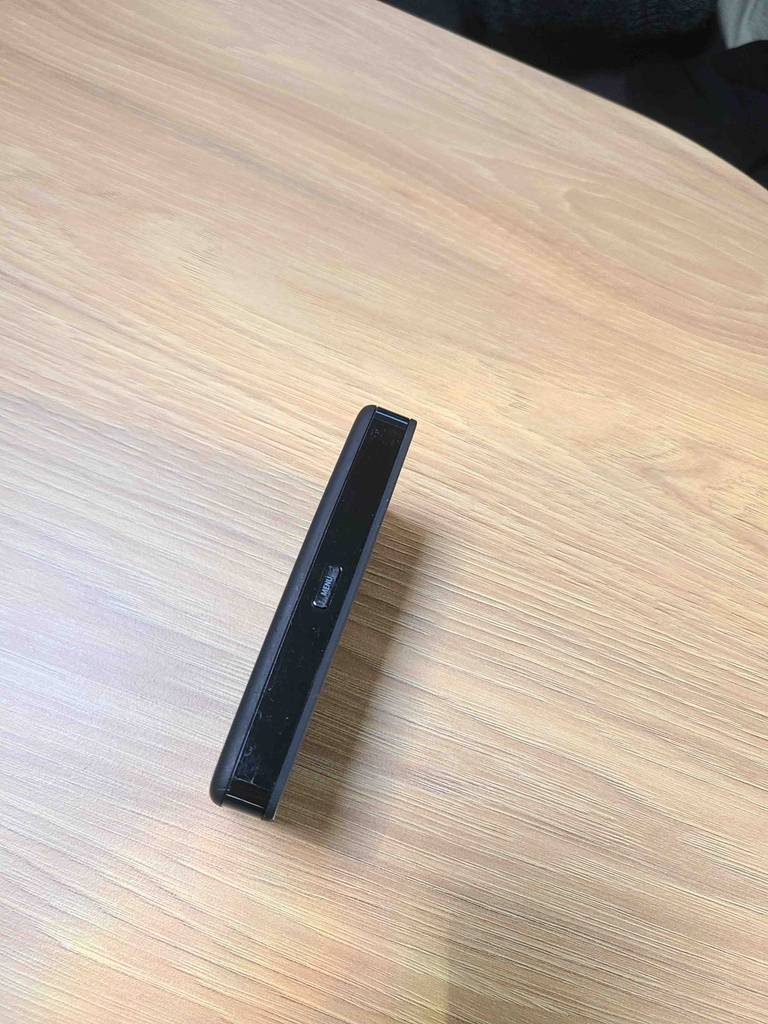 Der getestete, mobile WLAN-Router, von der schmalen Seite betrachtet, steht auf einer Holzoberfläche.
