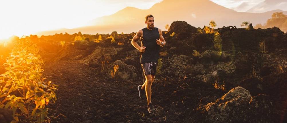 Trailrunningschuhe-Herren-Test: Ein Mann läuft auf einem unebenen Untergrund.