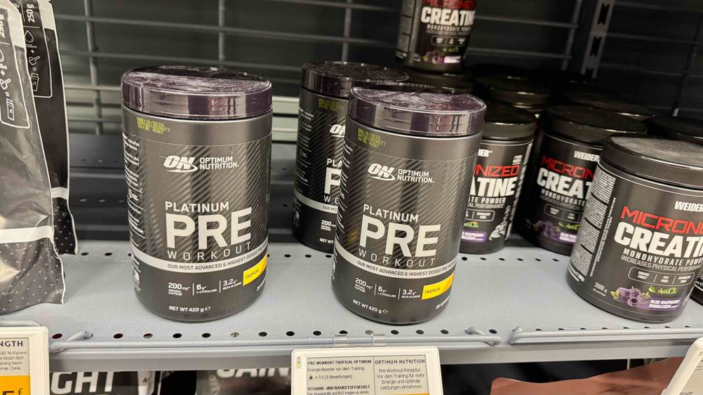 Mehrere Dosen des Trainingsboosters im Test auf einem Regal neben anderen Produkten.