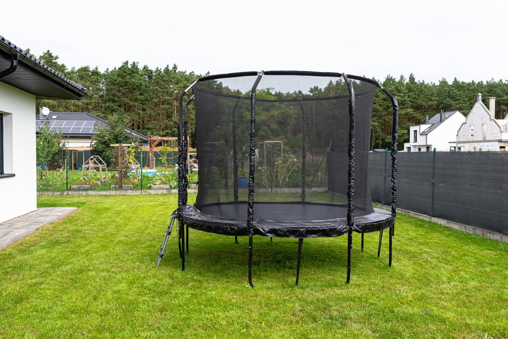 Trampolin-Sprungtuch-Test: Trampolin mit Schutznetz und geschlossenem Reißverschluss, das im Garten steht