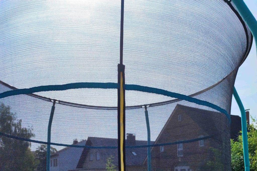 Das Netz eines getesteten Gartentrampolins mit Häusern im Hintergrund.
