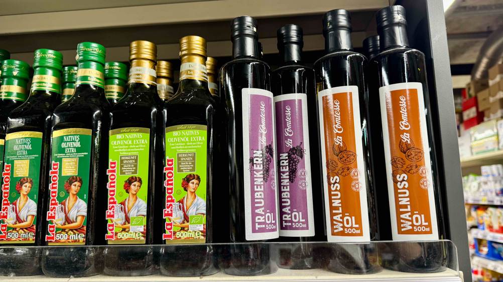 Traubenkernöl getestet: Mehrere Flaschen stehen neben anderen Produkten in einem Verkaufsregal.