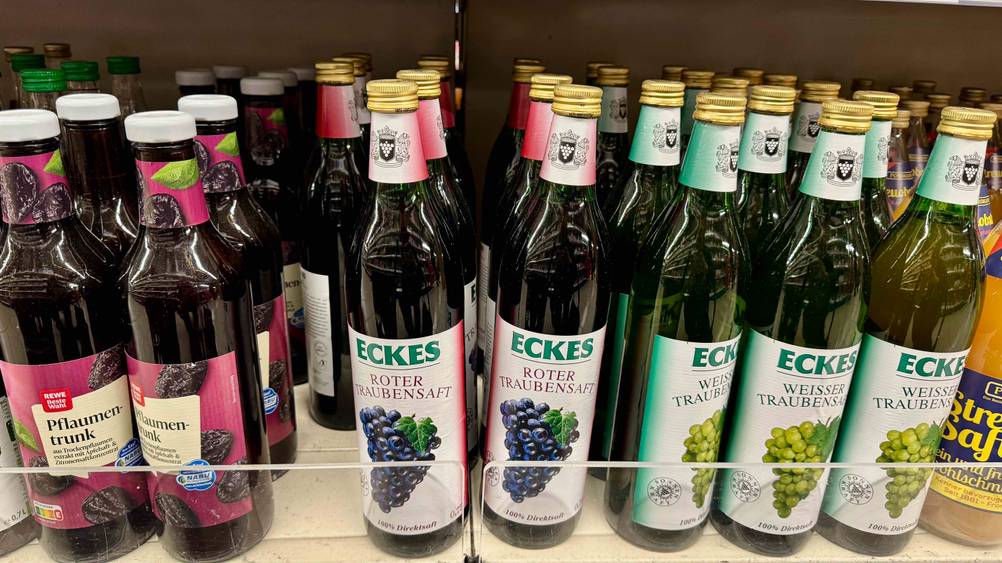 Mehrere Flaschen des getesteten Traubensaftes in einem Verkaufsregal neben anderen Produkten.