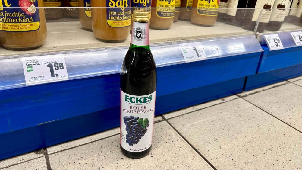 Eine Flasche des Traubensaftes im Test vor einem Verkaufsregal am Boden.