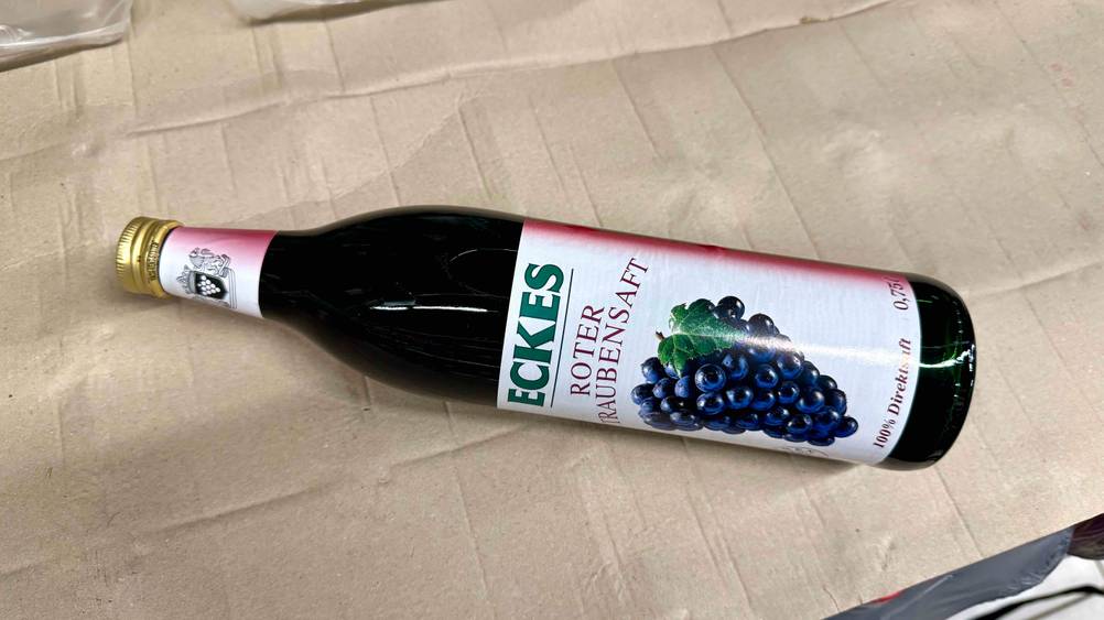 Eine Flasche des getesteten Traubensafts horizontal auf einem Karton.