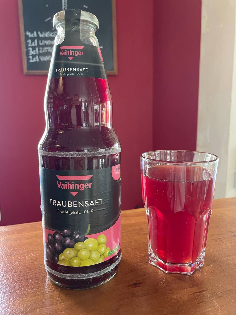 Neben einem Glas steht eine Flasche des getesteten Traubensaftes.
