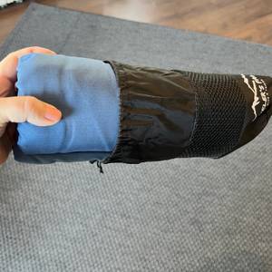 Blauer Hüttenschlafsack wird aus schwarzem Transportbeutel entnommen