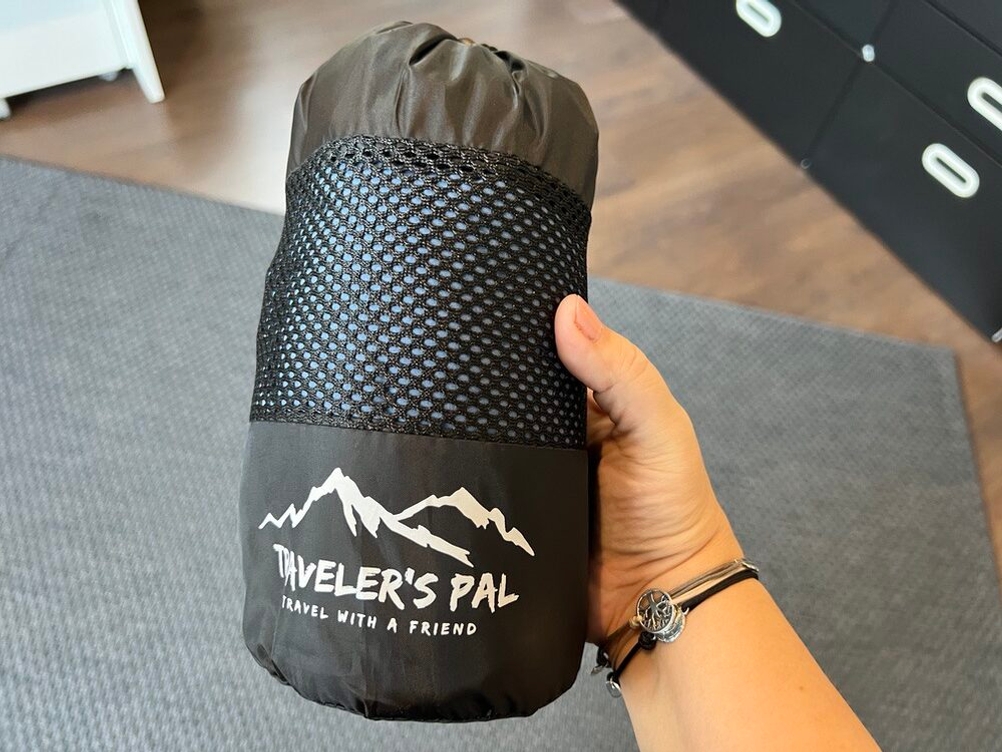 Traveler's-Pal-Hüttenschlafsack wieder in einem Transportbeutel verpackt, Hand hält ihn fest