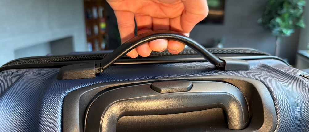 Eine Hand hebt den Travelite City am Tragegriff hoch