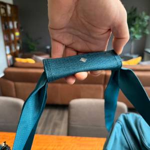 Eine Hand hebt die Travelite Kick Off am Gurt hoch.