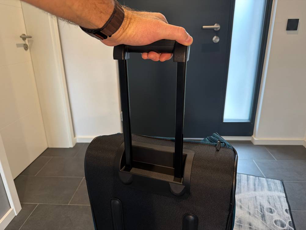 Eine Hand hält die Travelite Kick Off am ausgefahrenen Griff fest.