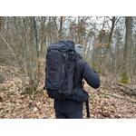 Der Vaude Asymmetric 42+8 wird von einer Person im Wald getragen. Der Rucksack liegt eng am Rücken an.