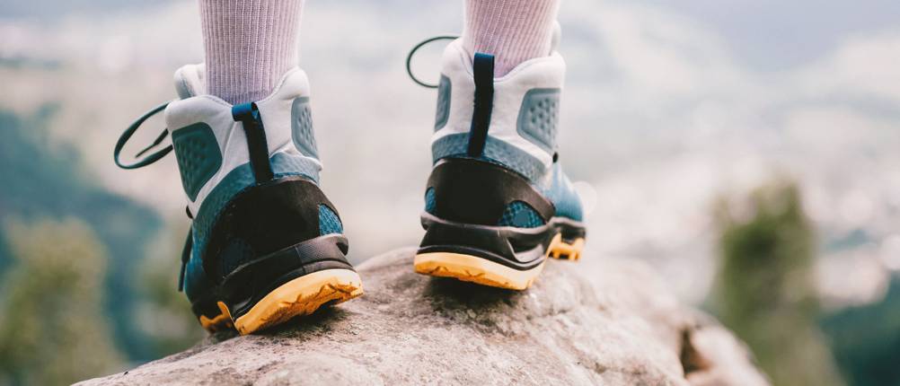 Trekkingschuhe Unisex im Test: Person steht auf einem Felsbrock. Der Fokus ist dabei auf die Trekkingschuhe gerichtet.