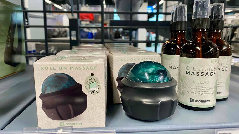 Handmassagegeräte-Test: ein schwarzes Modell mit grünem Roller befindet sich zwischen seiner Originalverpackung und Massageöl im Verkauf.