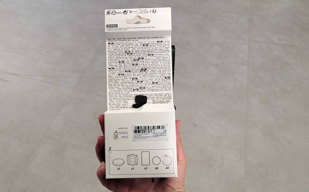 Handyhalterung für das Fahrrad im Test: Eine Hand zeigt die Rückseite einer Verpackung mit Hinweisen und Infos zum Inhalt und Handhabung.