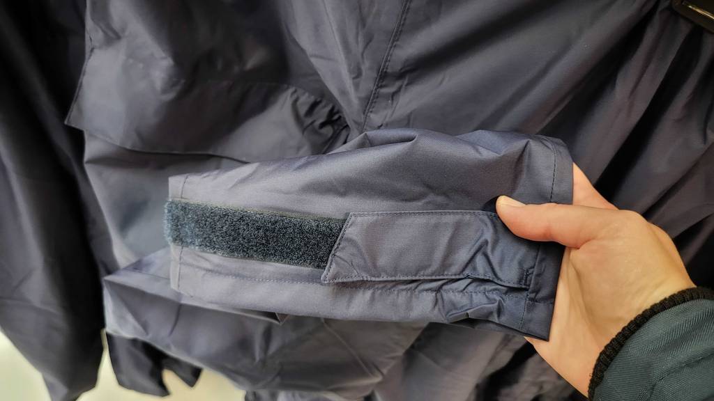 Hand greift nach getesteter Regenhose für Damen.