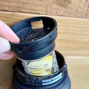 Ein schwarzer Siebdeckel wird von einer Hand auf den Fruchteinsatz der 720°Dgree uberBottle aufgesetzt. Die Flasche ist bereits befüllt.