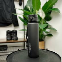Die 720°Dgree uberBottle steht aufgebaut auf einem schwarzen Tisch. Der Hintergrund zeigt Pflanzen und Wandhaken.