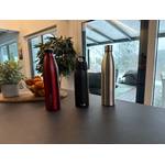 Drei Trinkflaschen aus Edelstahl stehen nebeneinander auf einem Tisch