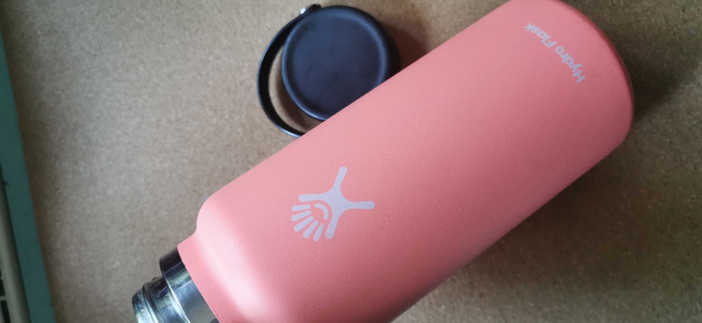 Pinke Edelstahl-Trinkflasche liegt mit geöffneten Deckel.