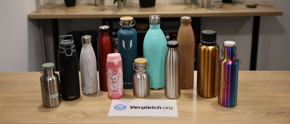 Mehrere Edelstahl-Trinkflaschen in unterschiedlichen Designs und Größen stehen auf einem Tisch