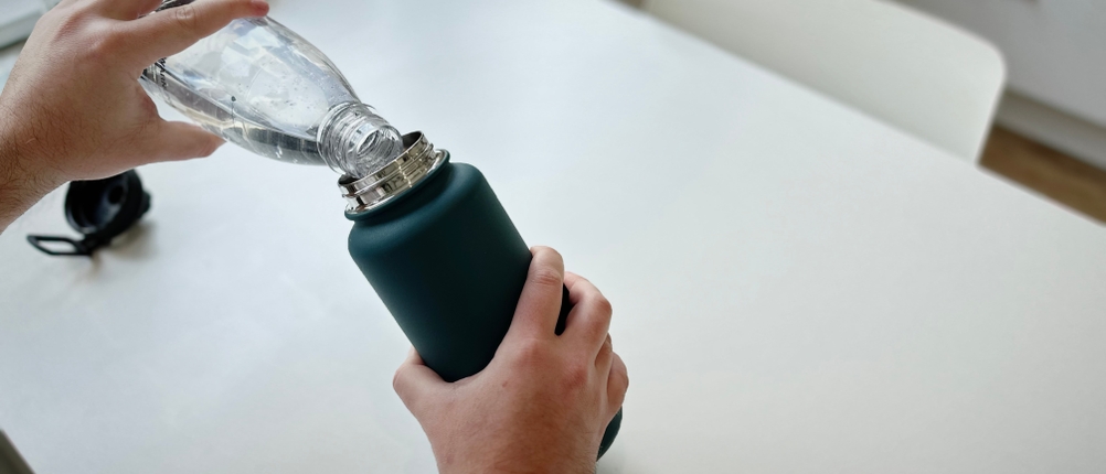 Es wird Wasser in die Trinkflasche geschüttet.