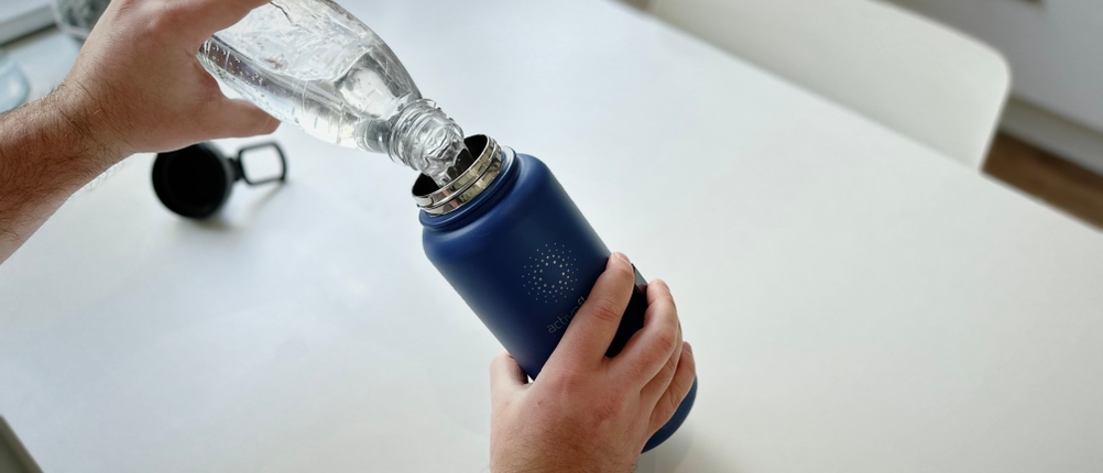 Es wird Wasser in die Trinkflasche geschüttet.