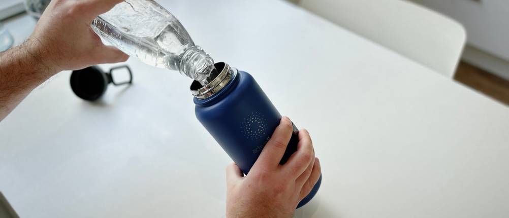 Es wird Wasser in die Trinkflasche geschüttet.