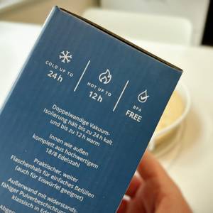 Die Verpackung der Trinkflasche von beMaxx wird mit einer Hand festgehalten.