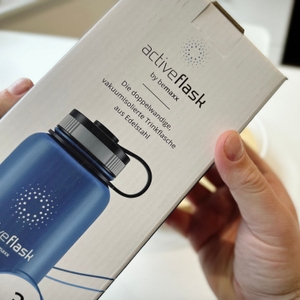 Eine Hand hält die Verpackung der Trinkflasche beMaxx.